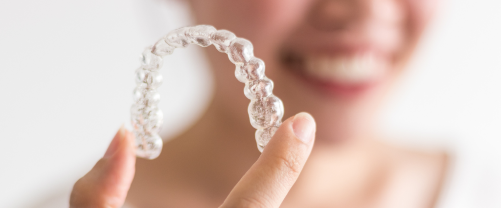 adult holds invisalign tray after learning about invisalign gum health