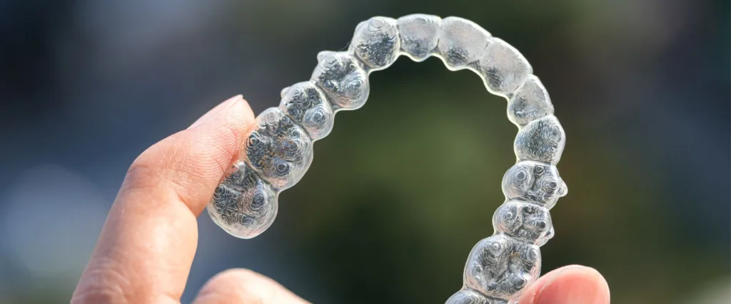 adult holds invisalign tray after getting invisalign in augusta, ga
