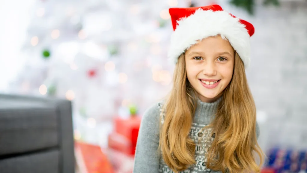 girl in santa hat smiles and listens in to stocking stuffer ideas
