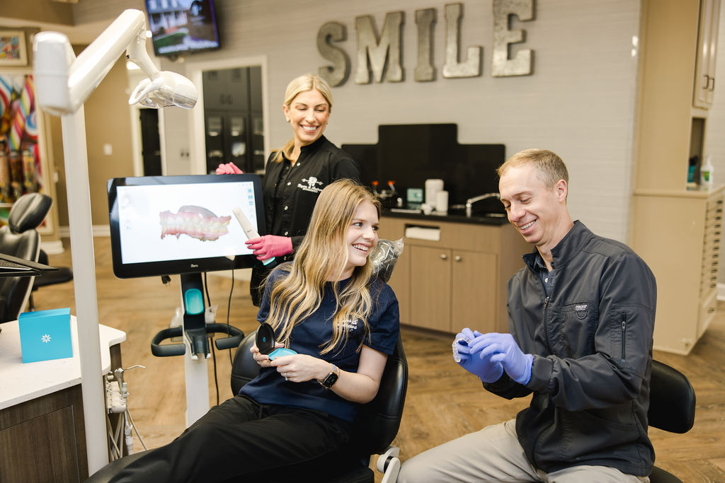 Dr. Andrews smiling with patient in exam chair, showing patient dental model, how to clean Invisalign 101 with Rogers & Andrews Orthodontics
