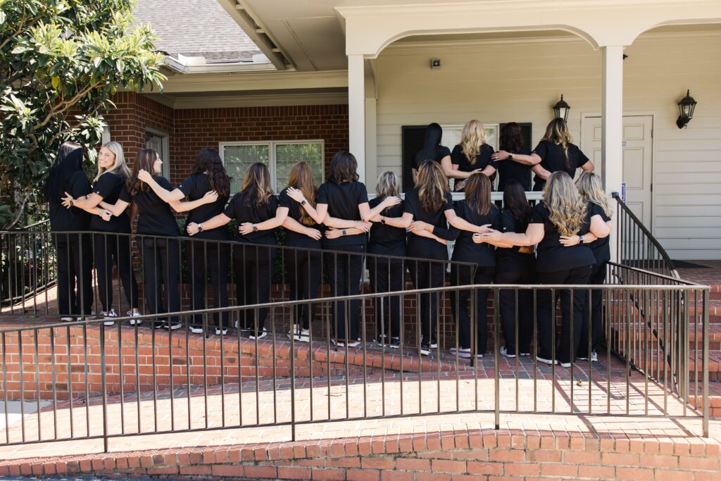 Rogers & Andrews Orthodontics team on the patio holding arms, invisalign augusta grovetown GA