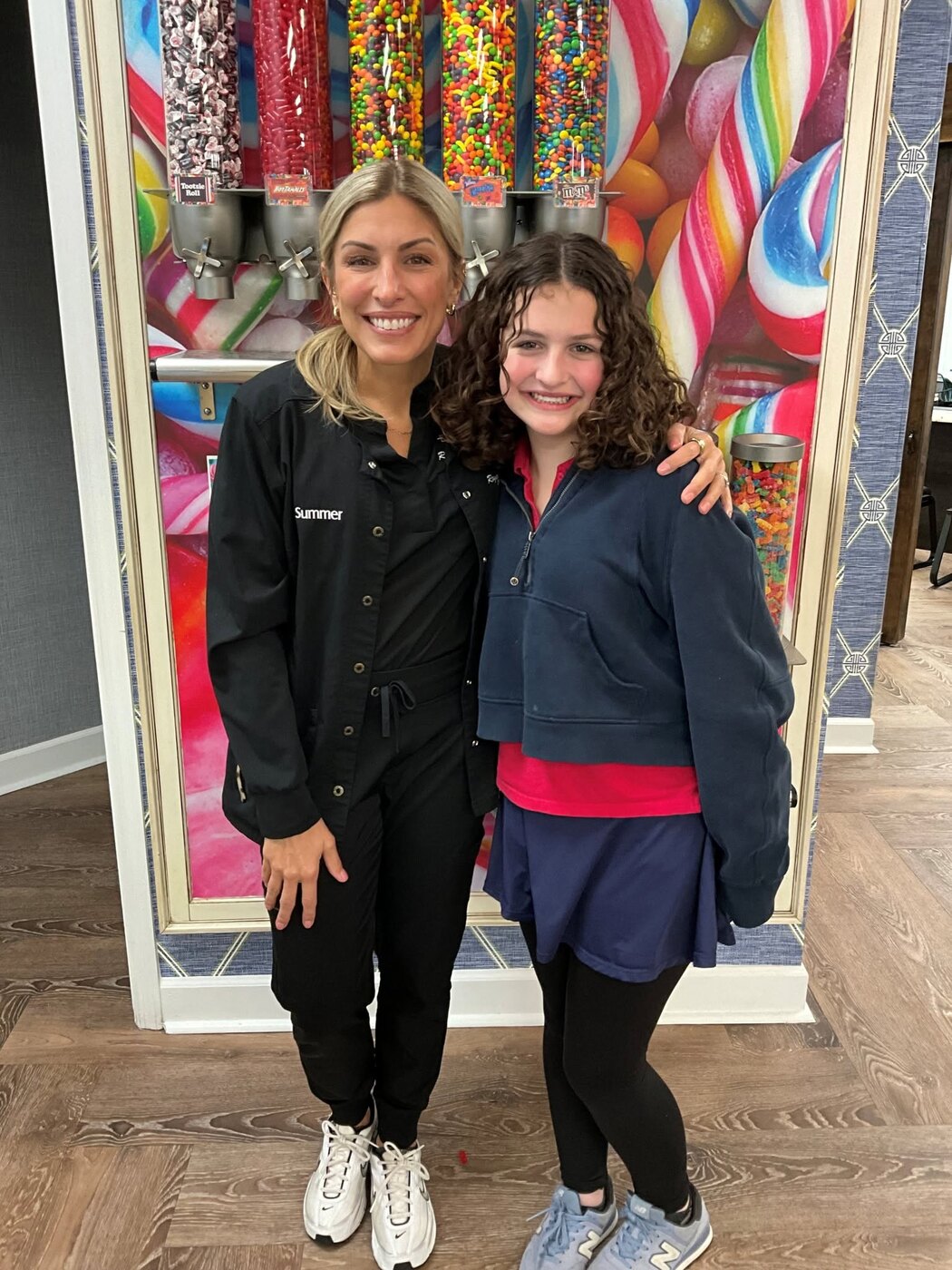 A team member and smiling patient at the Rogers & Andrews candy wall